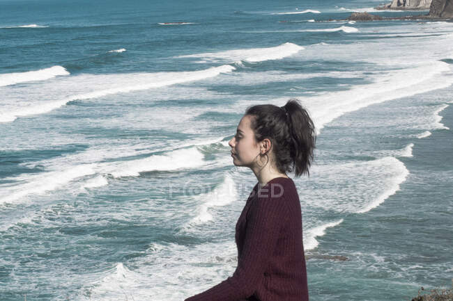 Chica meditando en la orilla con olas - foto de stock