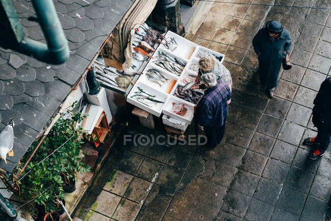 Du vendeur ci-dessus montrant le poisson au client au comptoir sur un marché. — Photo de stock