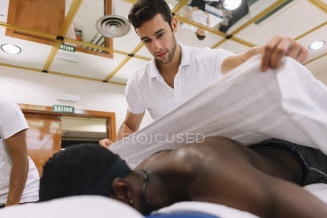 O fisioterapeuta tratando um homem usando equipamentos para radioterapia — Fotografia de Stock