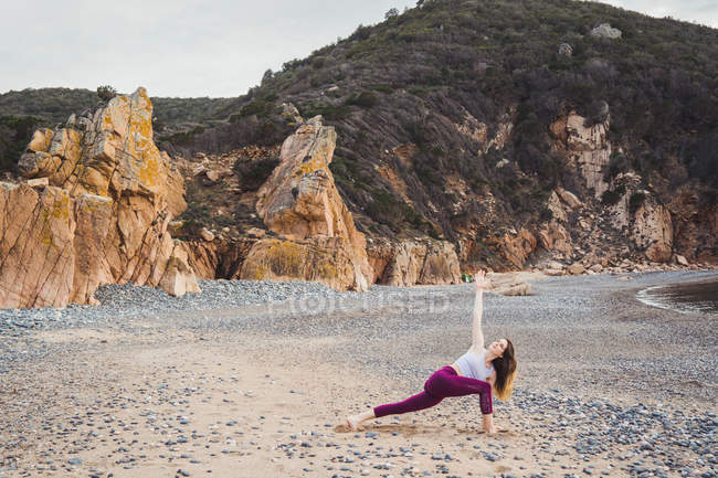 Mulher apto exercício na praia rochosa — Fotografia de Stock