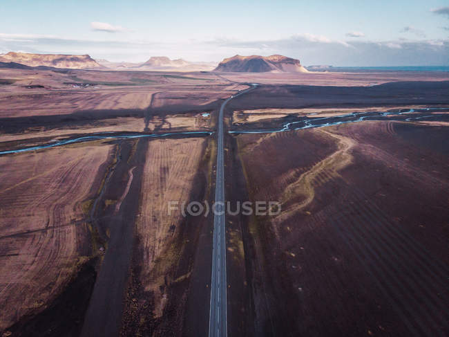 Camino en tierra sombría y montañas en el fondo, Islandia - foto de stock