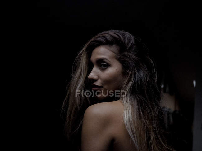 Sensual mujer en la oscuridad mirando hacia atrás - foto de stock