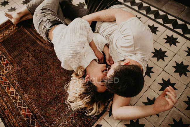 Счастливые мужчина и женщина лежат на полу и целуются дома — стоковое фото