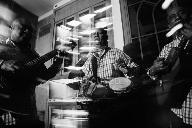 Cuban musical trio acting in night club, black and white shot with long exposure — Stock Photo