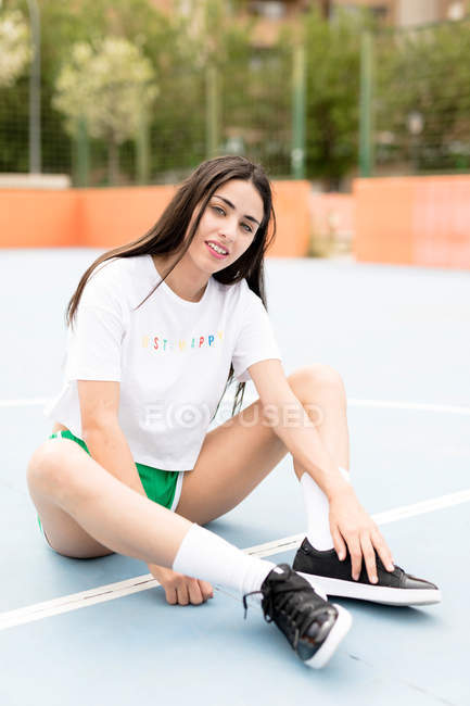 Портрет молодой женщины, сидящей на спортивной площадке — стоковое фото