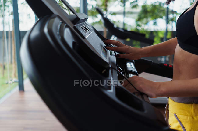 Hands of sporty woman setting race track in gym — Stock Photo