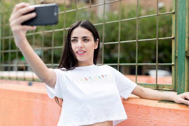 Junge schlanke Frau steht und macht Selfie auf Sportplatz — Stockfoto