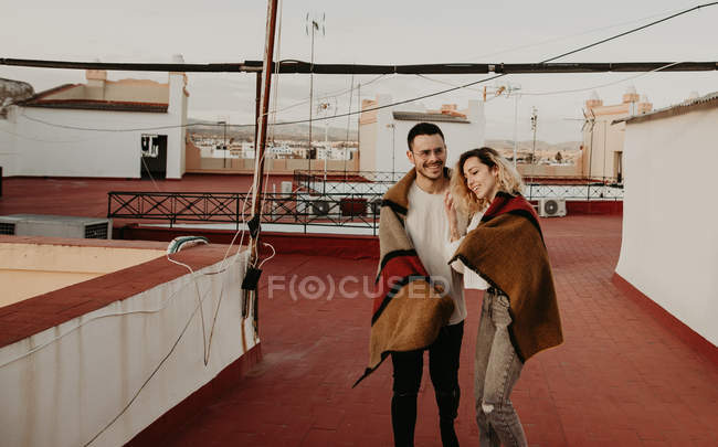 Couple with blanket having fun on terrace in old city — Stock Photo