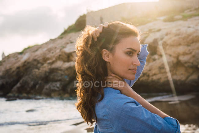 Женщина с длинными каштановыми волосами стоит на пляже — стоковое фото