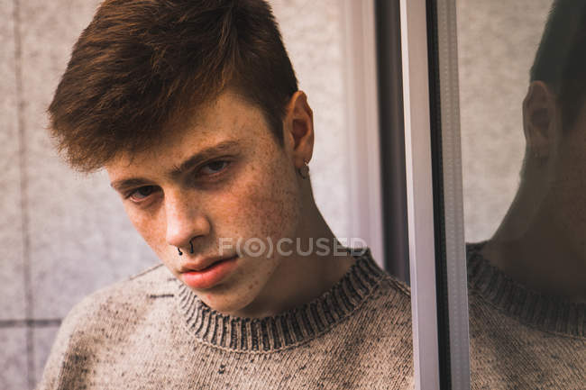 Sensuale giovane uomo con lentiggini appoggiata alla finestra — Foto stock