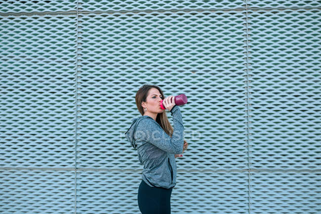 Porträt einer jungen Sportlerin mit Wasserflasche vor dem Netz — Stockfoto