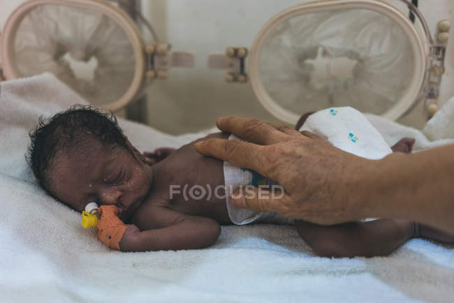 CAMARÕES - ÁFRICA - 5 de abril de 2018: tocar a mão na criança étnica recém-nascida em caixa estéril no hospital — Fotografia de Stock