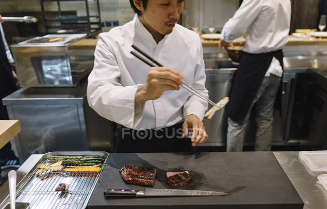 Chef préparant le plat avec des baguettes au restaurant — Photo de stock