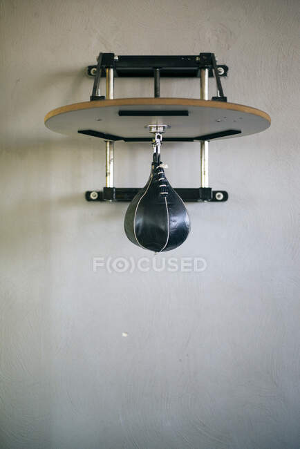 Small punch bag for stamina exercise hanging on gray wall. — Stock Photo