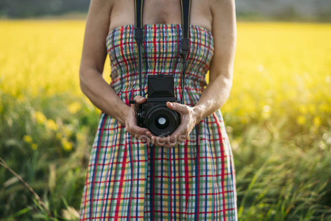 Frau in farbigem Kleid hält Fotoapparat in der Natur — Stockfoto