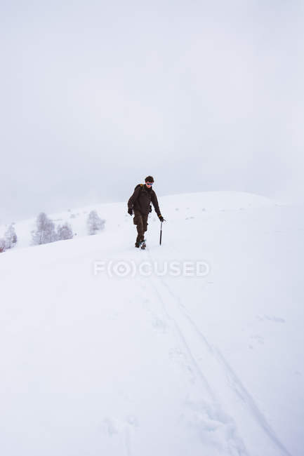 Turista con zaino arrampicata su montagna innevata — Foto stock