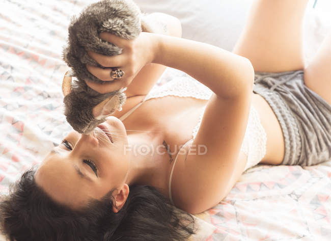 Mujer joven acostada en la cama con chinchilla - foto de stock