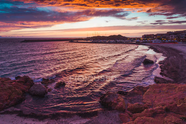 Ciel spectaculaire au coucher du soleil et ville sur la côte, Sardaigne, Italie — Photo de stock