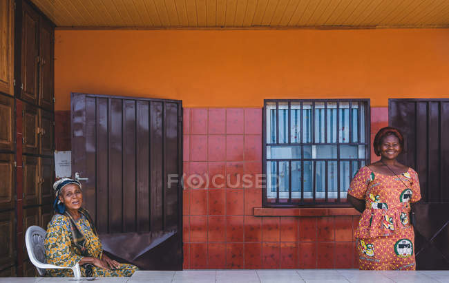 КАМЕРУН - Африка - 5 апреля 2018 года: Улыбающиеся этнические женщины, стоящие и сидящие в доме — стоковое фото