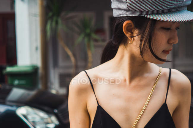 Retrato de jovem mulher asiática em boné olhando para longe — Fotografia de Stock