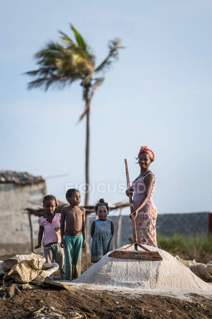 АНГОЛА - Африка - 5 апреля 2018 года - жизнерадостная африканская женщина, работающая на ферме, и дети, стоящие рядом — стоковое фото