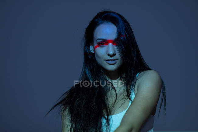 Молода приваблива жінка з червоною лінією на обличчі, стоячи на сірому фоні — стокове фото