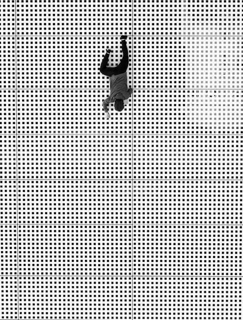 Black and white from above shot of man in casual outfit crawling on surface of pavement in tiny cube pattern — Stock Photo