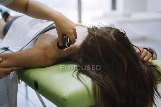 Le physiothérapeute traitant une femme utilisant un équipement de radiothérapie — Photo de stock