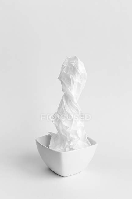 Wrinkled paper on ceramic bowl composition on white background — Stock Photo