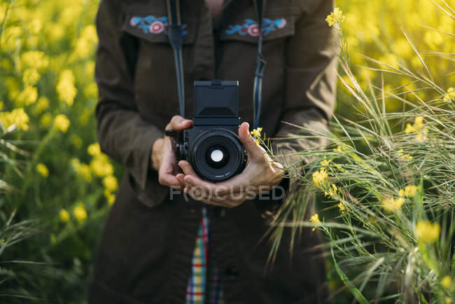 Frau in Jacke hält Fotoapparat in der Natur — Stockfoto