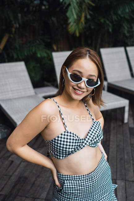Портрет улыбающейся женщины в солнечных очках, стоящей перед шезлонгами — стоковое фото