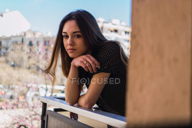 Портрет Мрійливої молодої брюнетки, що стоїть на балконі — стокове фото