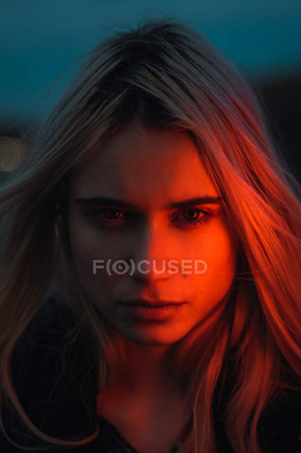 Mulher loira pensativa olhando para a câmera no crepúsculo — Fotografia de Stock