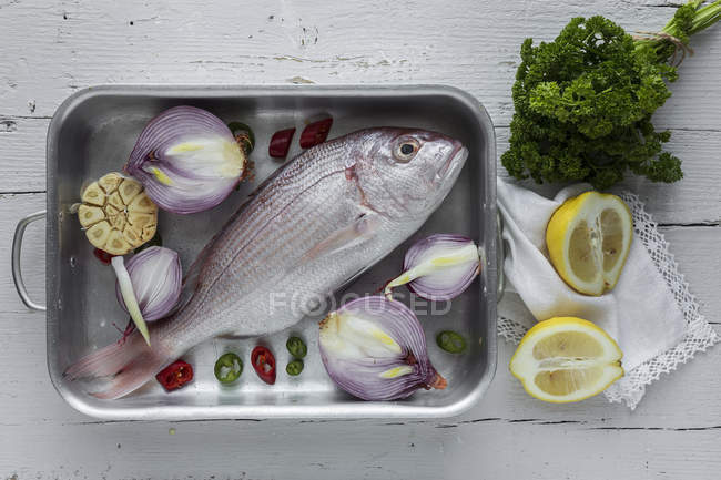 Produtos hortícolas e peixe-dourado cru na assadeira — Fotografia de Stock