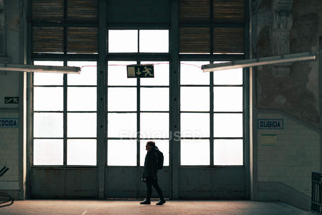 Мужчина турист, стоящий у большой светлой двери в здании с камерой — стоковое фото