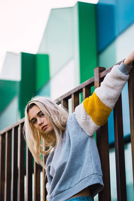 Stilvolle junge Frau lehnt an Wand gegen moderne Häuser — Stockfoto