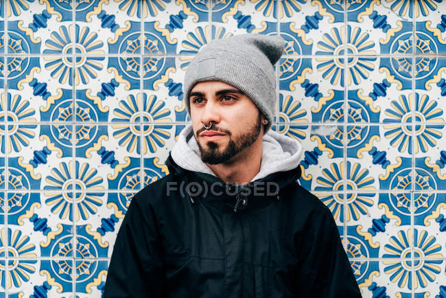 Portrait de touriste masculin réfléchi debout au mur avec des tuiles bleues — Photo de stock
