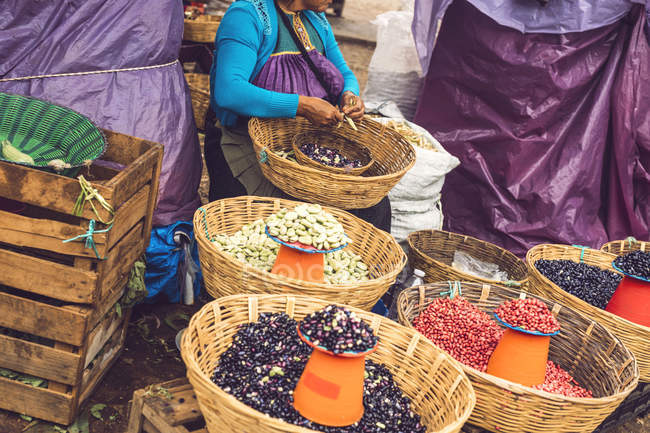 Мексиканка сидит на рынке и чистит свежие бобы для продажи — стоковое фото