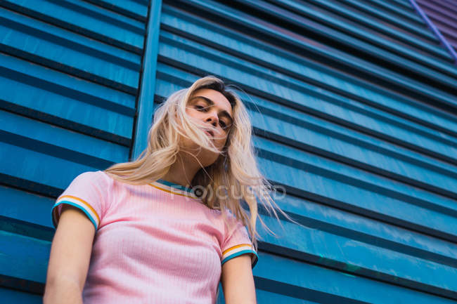 Portrait de jeune femme blonde penchée sur un mur bleu dans la rue — Photo de stock