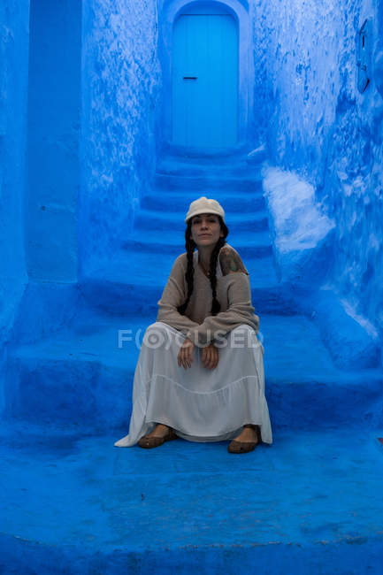 Portrait of woman sitting on blue dyed street, Morocco — Stock Photo