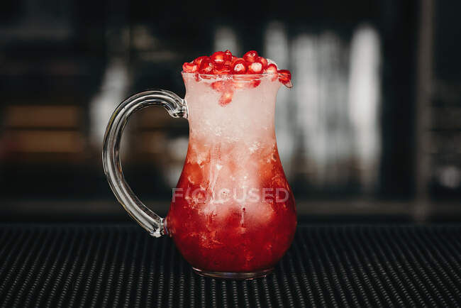 Glaskrug voller erfrischender Limonade aus roten Beeren auf der Theke in der Bar. — Stockfoto