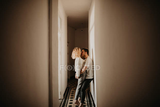 Счастливая пара обнимает и целует в холле дома — стоковое фото