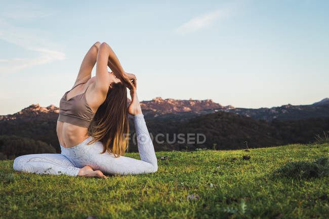 Frau dehnt sich und macht Yoga auf Rasen in der Natur — Stockfoto