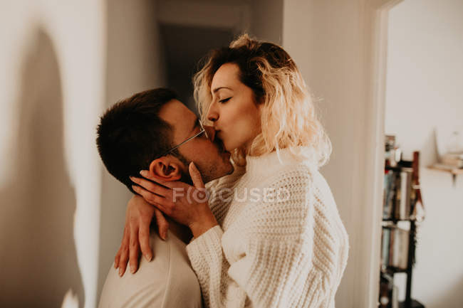 Passionate couple embracing and kissing at wall at home — Stock Photo