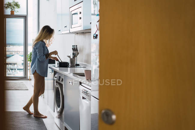 Cheerful sensual young woman making breakfast in kitchen — Stock Photo