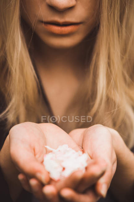 Nahaufnahme weiblicher Hände mit zartrosa Blütenblättern — Stockfoto