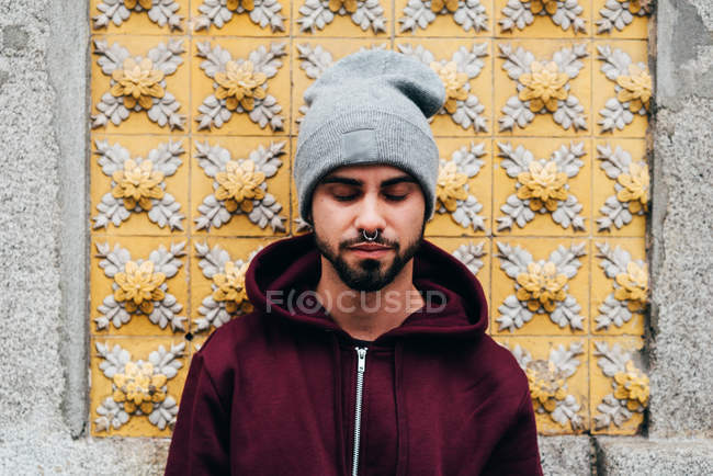 Портрет красивого молодого человека, стоящего у стены с желтой черепицей — стоковое фото