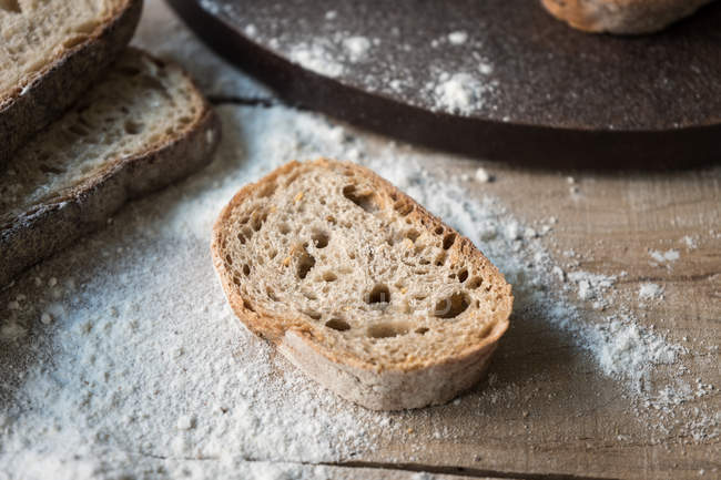 Fetta di pane fresco e appetitoso in farina su tavola di legno grezzo — Foto stock