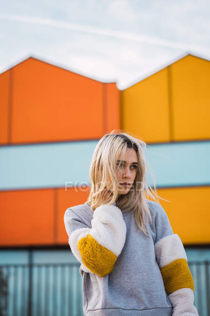 Mulher loira pensativa em pé em casas coloridas — Fotografia de Stock
