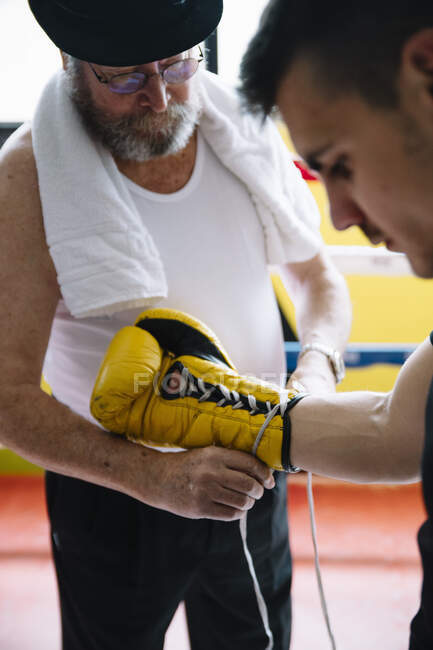 Тренер дорослих зав'язує боксерську рукавичку на руці спортсмена на рингу.. — стокове фото